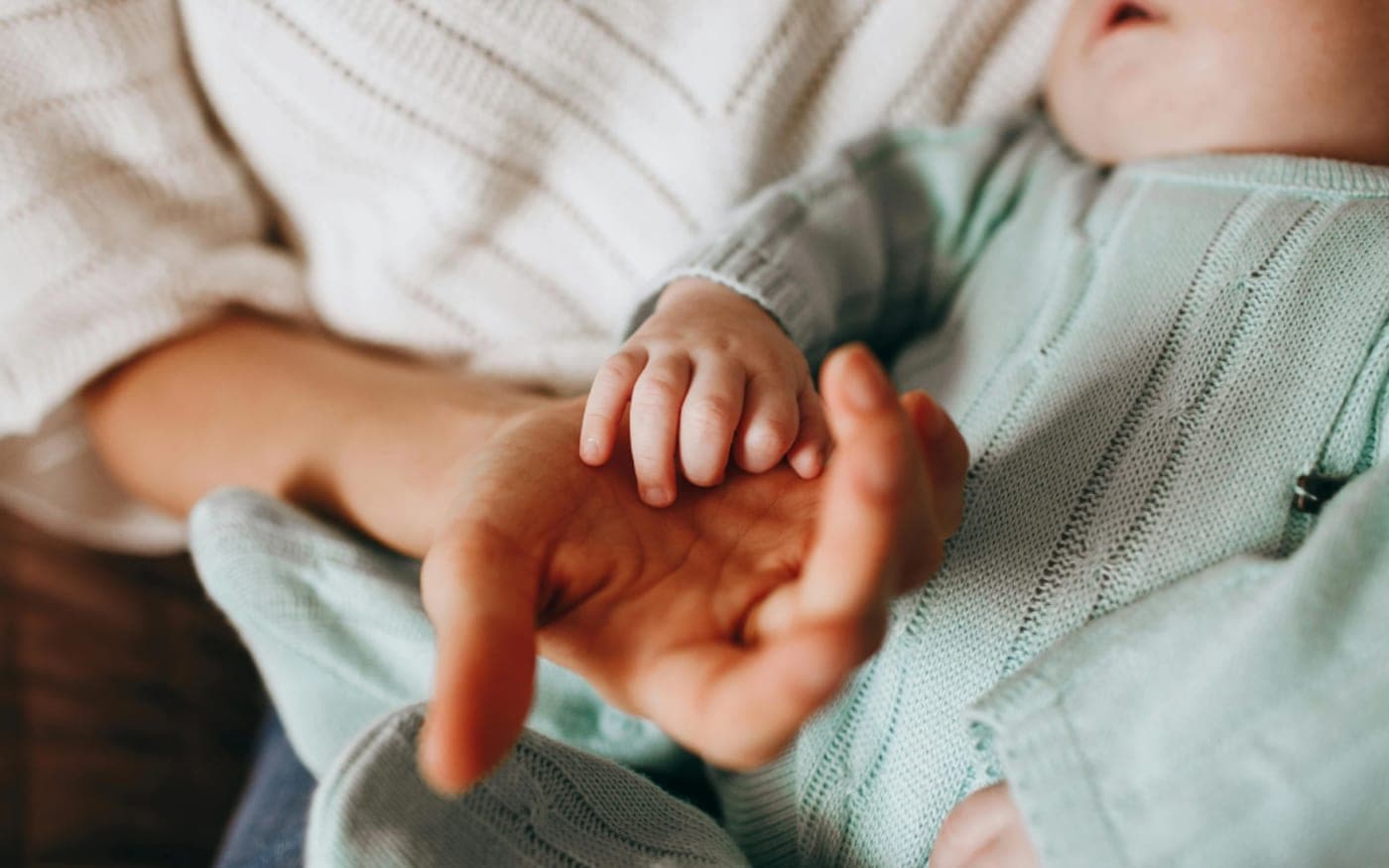 La main d’un nouveau-né refermée sur le doigt d’un adulte.