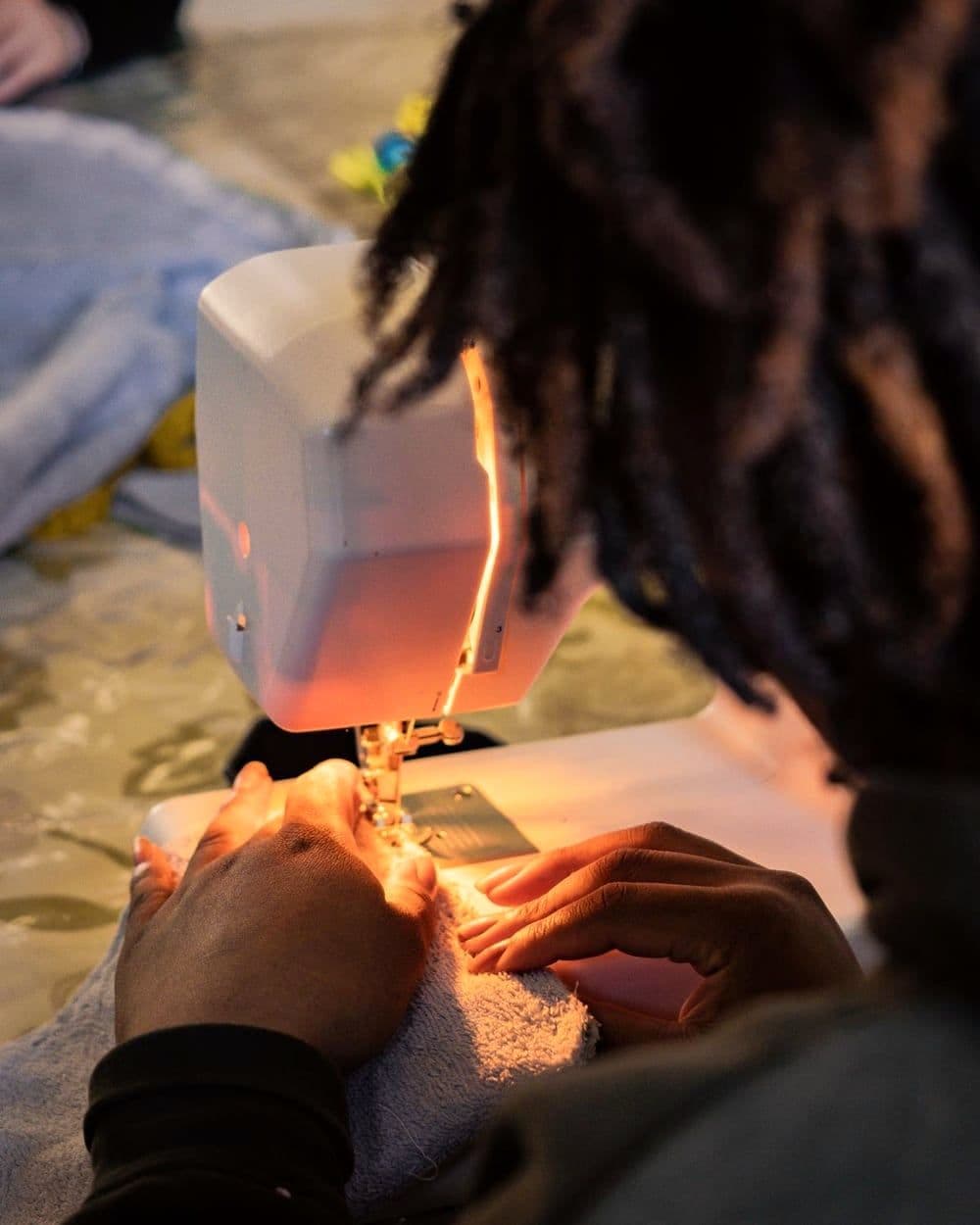 Une jeune femme accueillie coud à la machine pendant l’atelier couture.