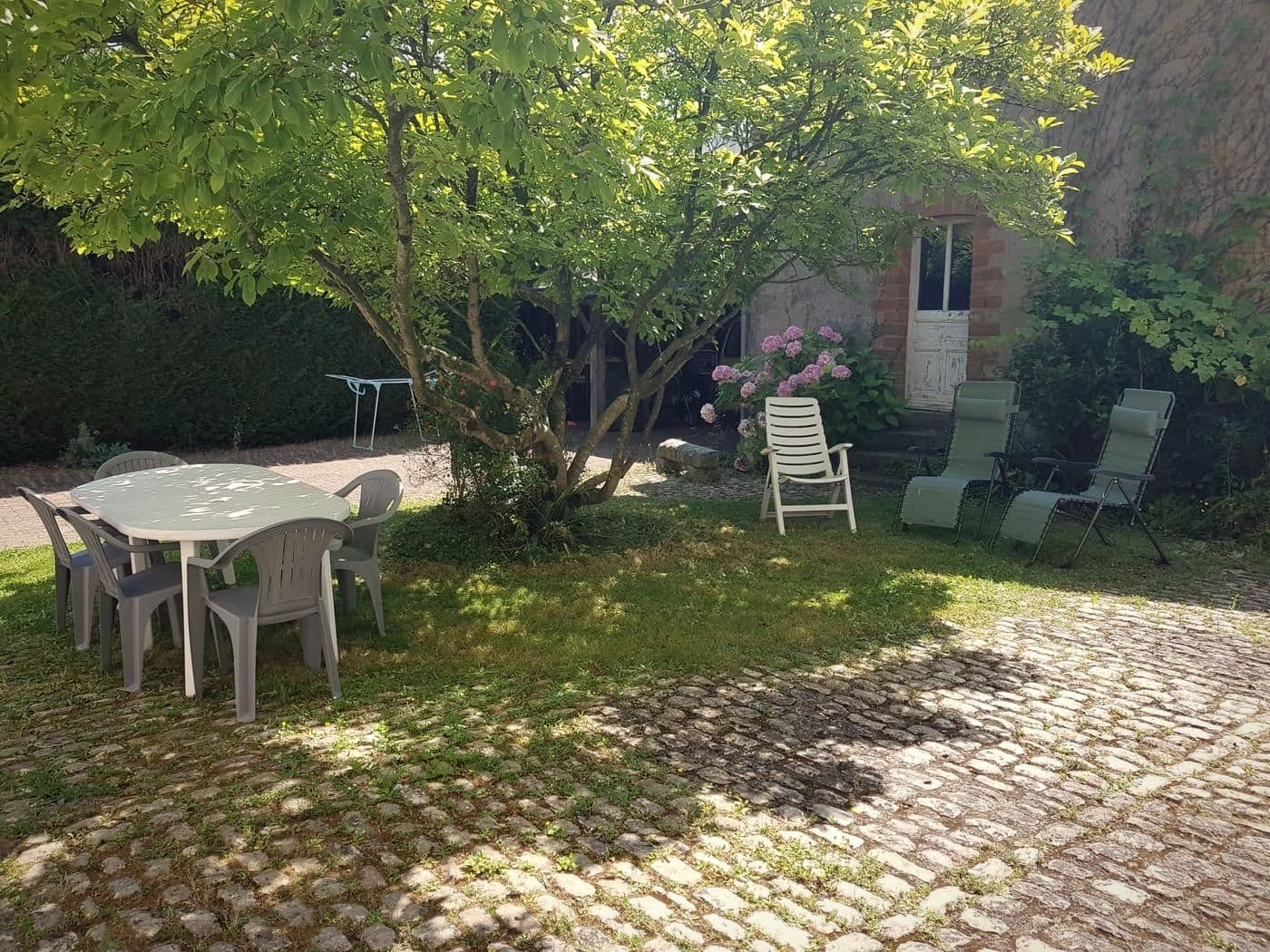 Le jardin clos de Laval, avec une table de jardin sous un arbre, devant la maison.