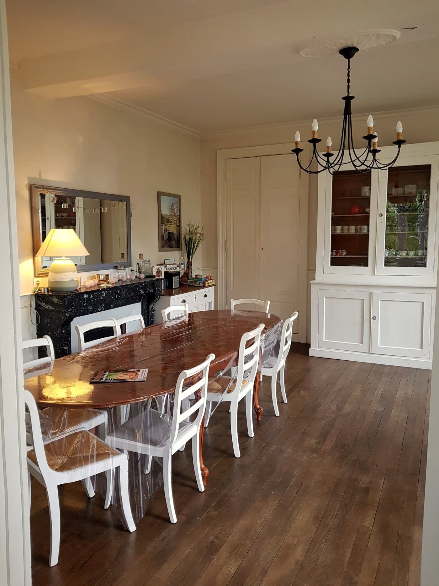 La salle à manger de Laval : une grande table ovale, une cheminée de marbre et un vaisselier.