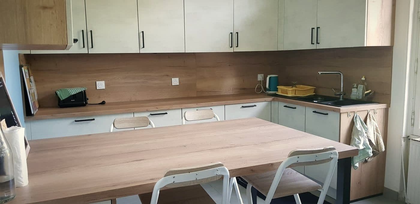 La cuisine commune de Ligueil, claire, avec un grand plan de travail en bois et des tabourets.