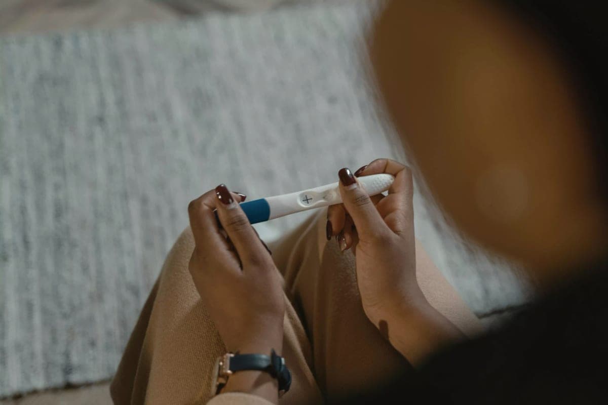 Les mains d’une femme qui tient un test de grossesse.
