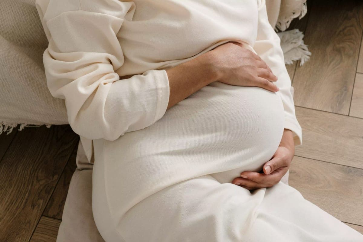 Une femme enceinte, les mains posées sur son ventre.